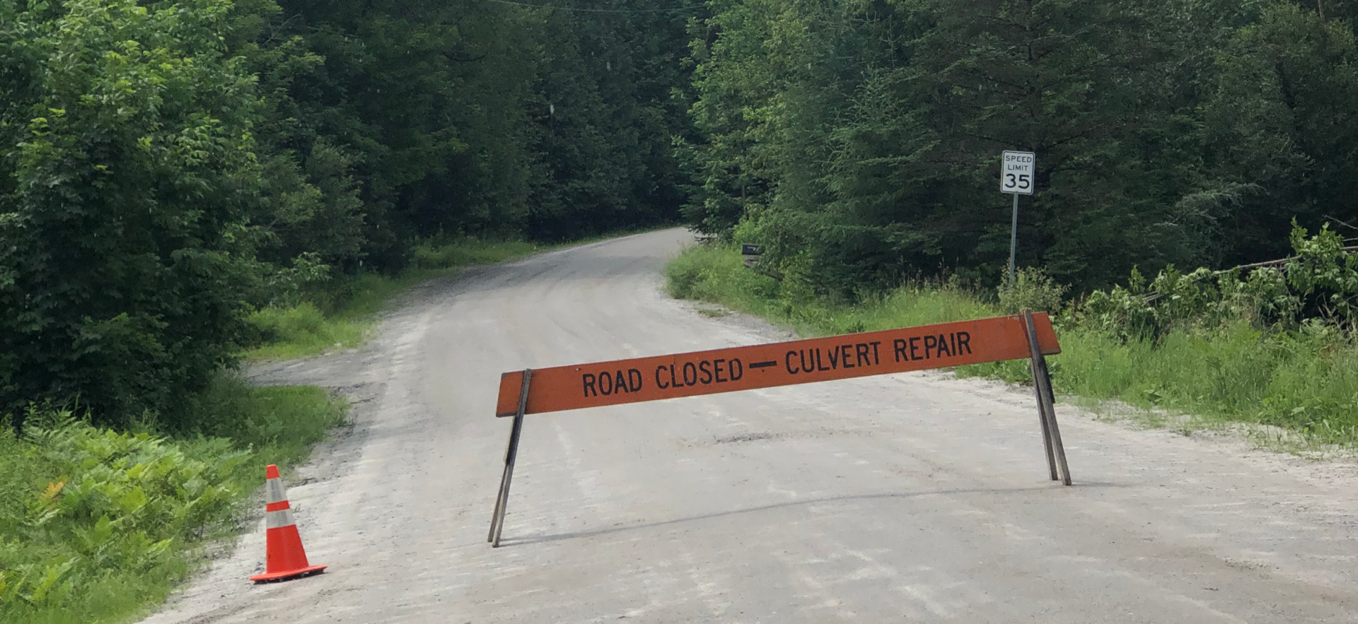 Orange road-closed sign blocking a rural Vermont dirt road for culvert repairs.