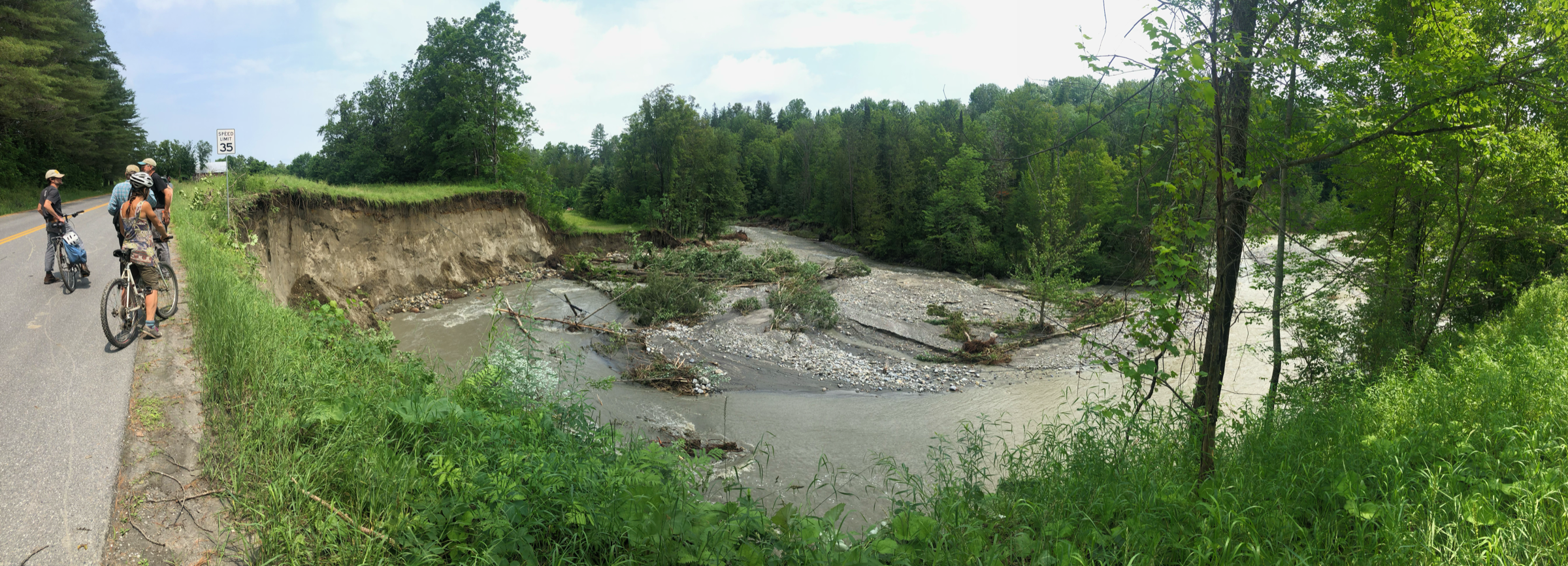 River bend washout where floodwaters carved a channel dangerously close to the gravel road.